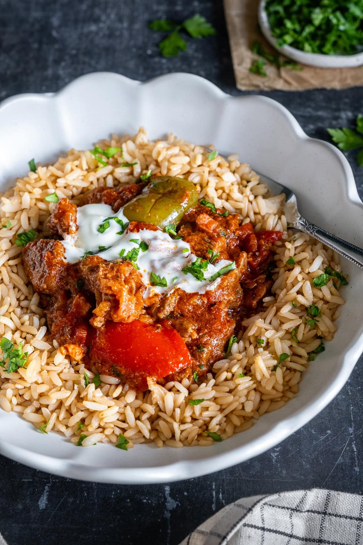 Closeup of Easy Hungarian Beef Goulash served on brown rice, with sour cream and parsley.