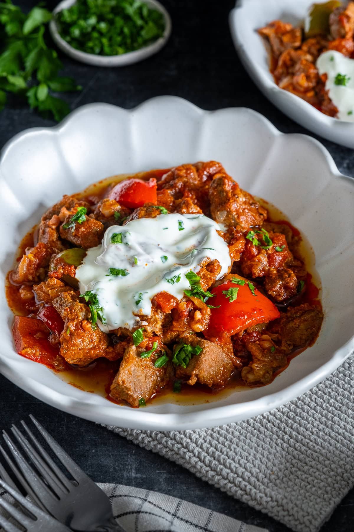 Closeup of Easy Hungarian Beef Goulash in a bowl with sour cream and parsley.