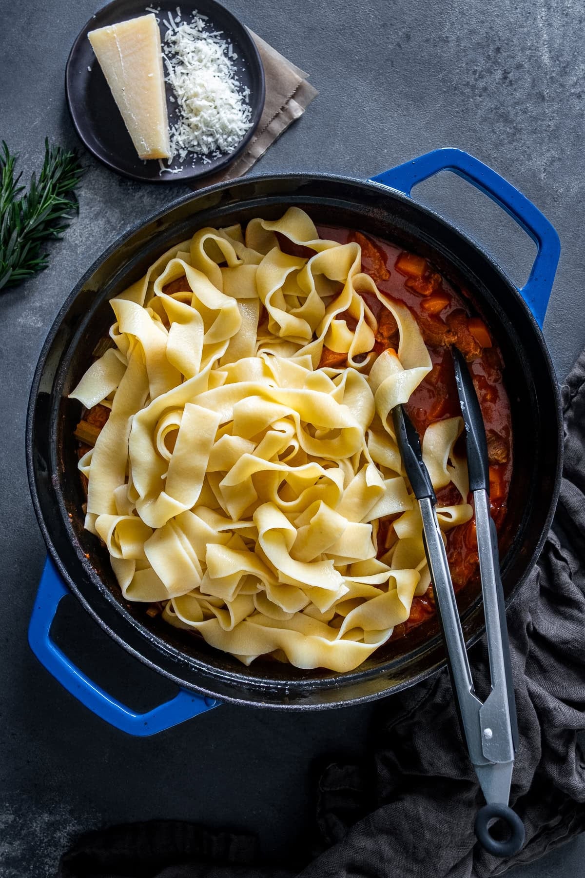 Overhead shot of pappardelle pasta being stirred into Leftover Lamb Ragu.