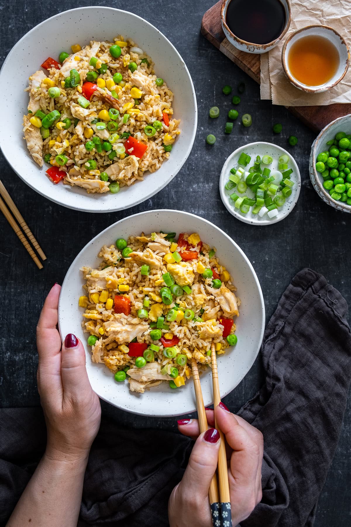 Overhead shot of Leftover Chicken Fried Rice with a woman's hands holding chopsticks.