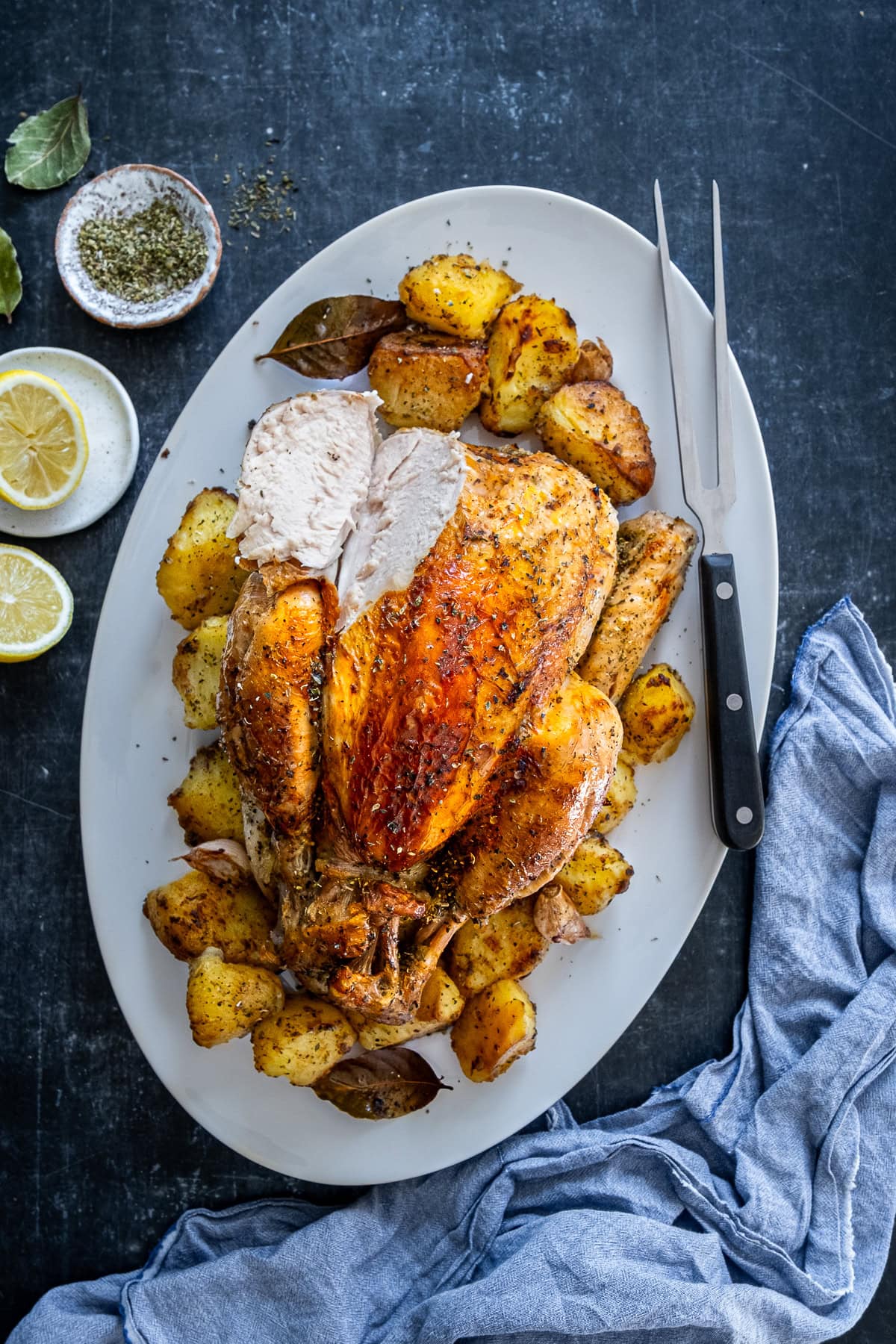 Overhead shot of One Pan Greek Roast Chicken and Roast Potatoes. A slice has been carved from the chicken.