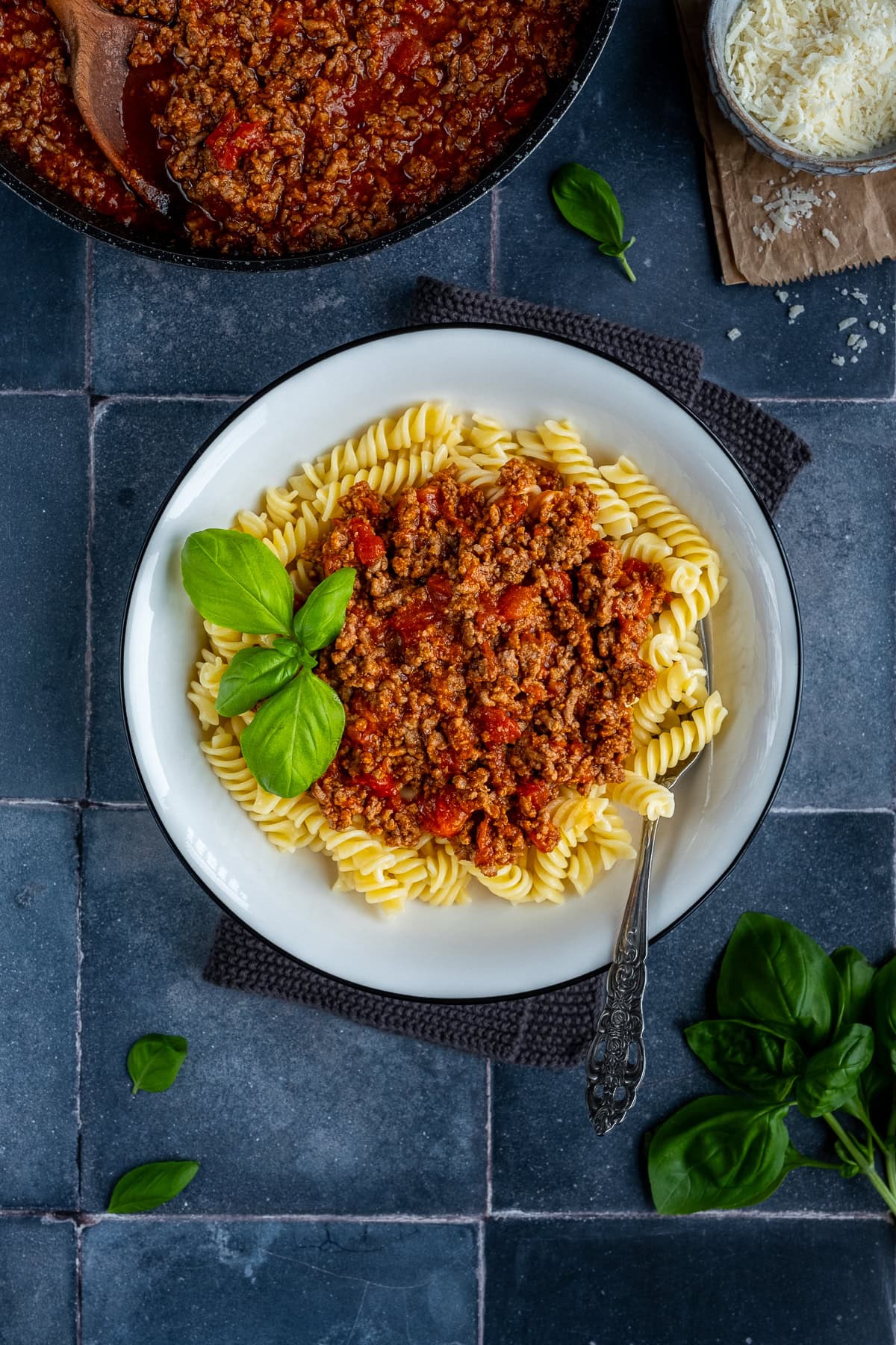 Overhead shot of Fusilli Bolognese in a bowl with basil.