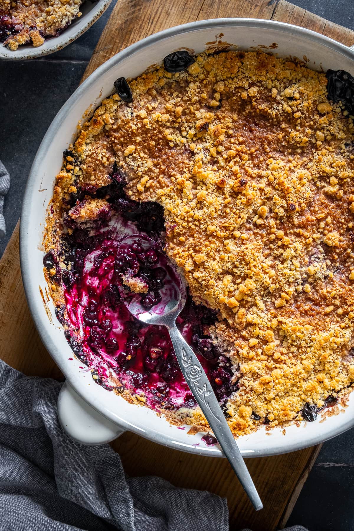 Overhead closeup shot of Easy Blueberry Crumble in the oven dish. One portion has been taken out.