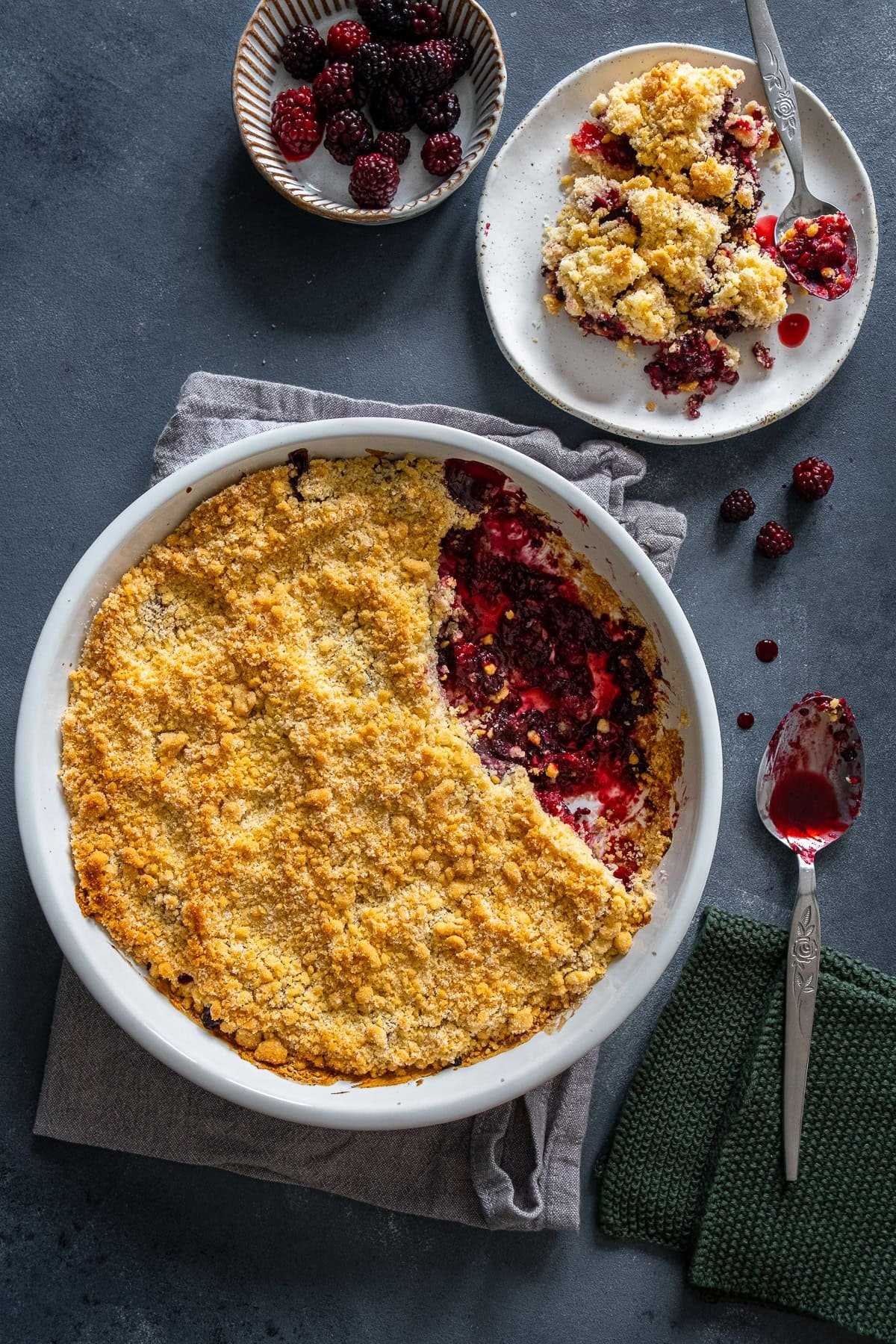 Overhead shot of Easy Blackberry Crumble in the dish and 1 portion on a plate.