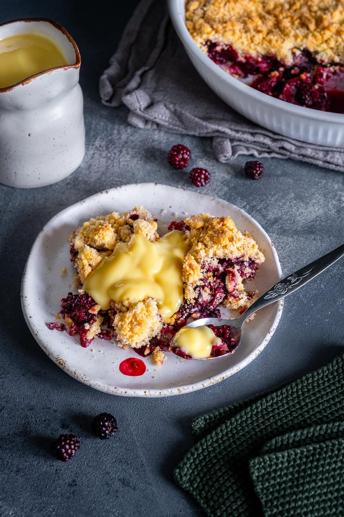 Easy Blackberry Crumble on a plate with custard.