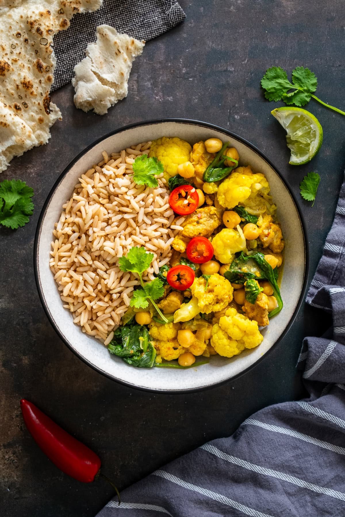 Overhead shot of Chicken and Chickpea Curry with Spinach in a bowl with brown rice.