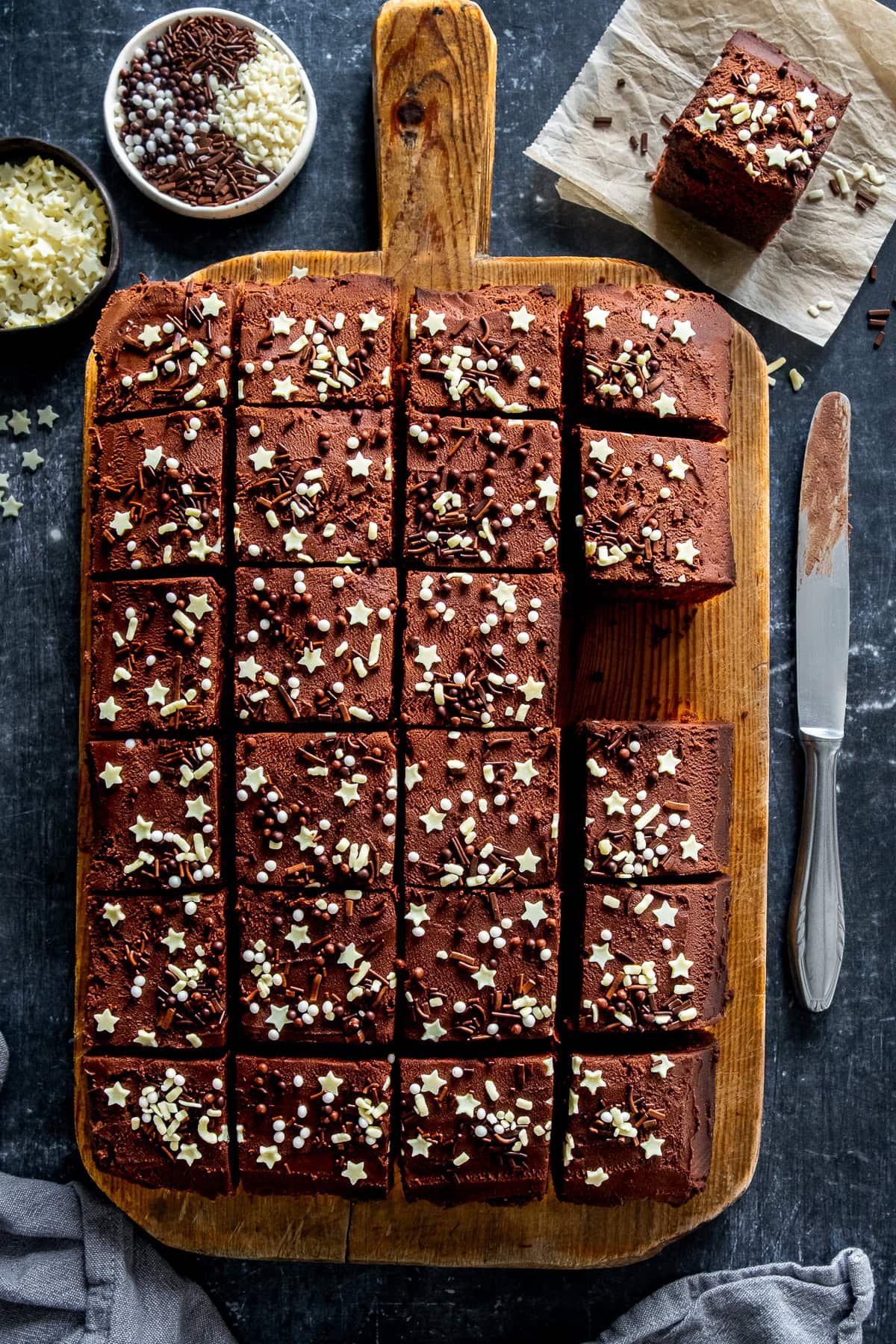 Easy Chocolate Traybake Cake cut up into slices on a board.