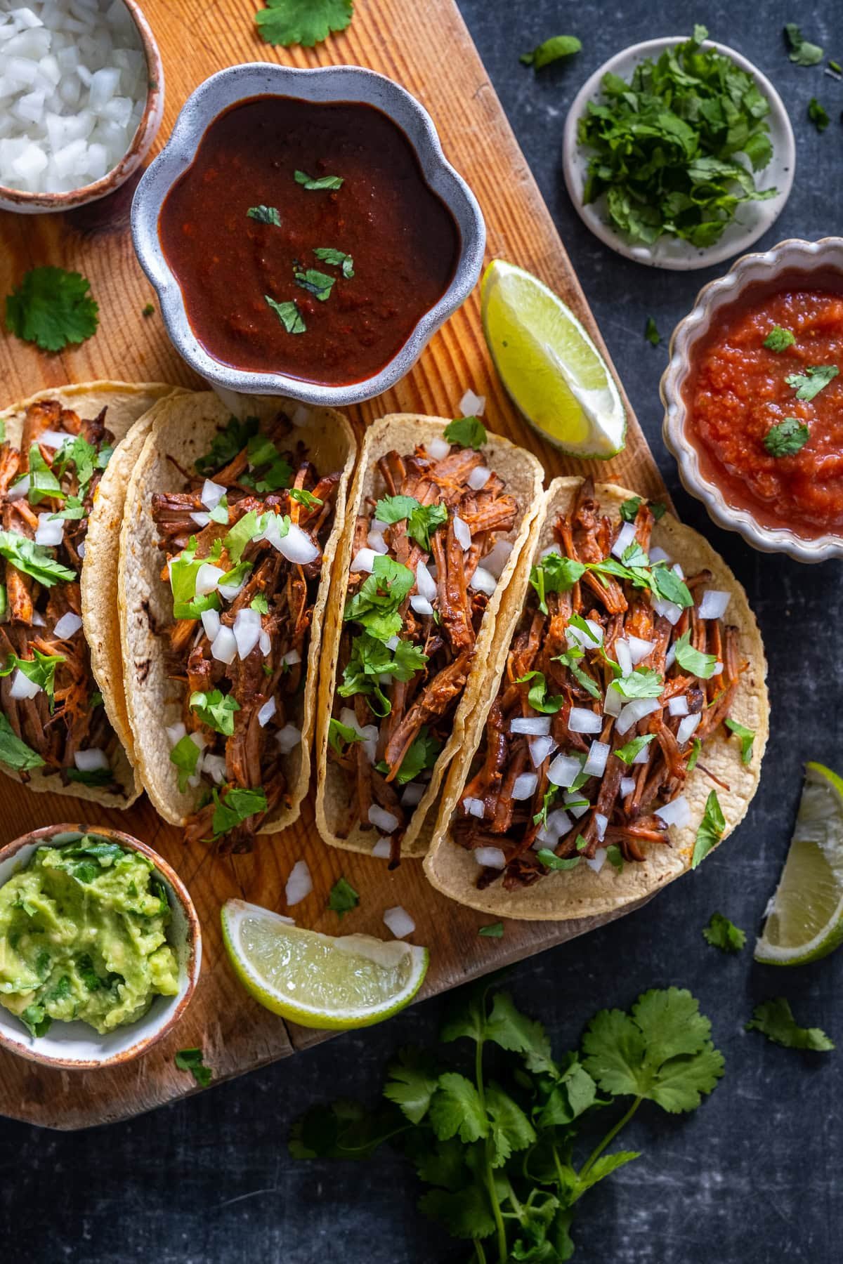 4 Easy Beef Birria Tacos on a board with a small bowl of consome.