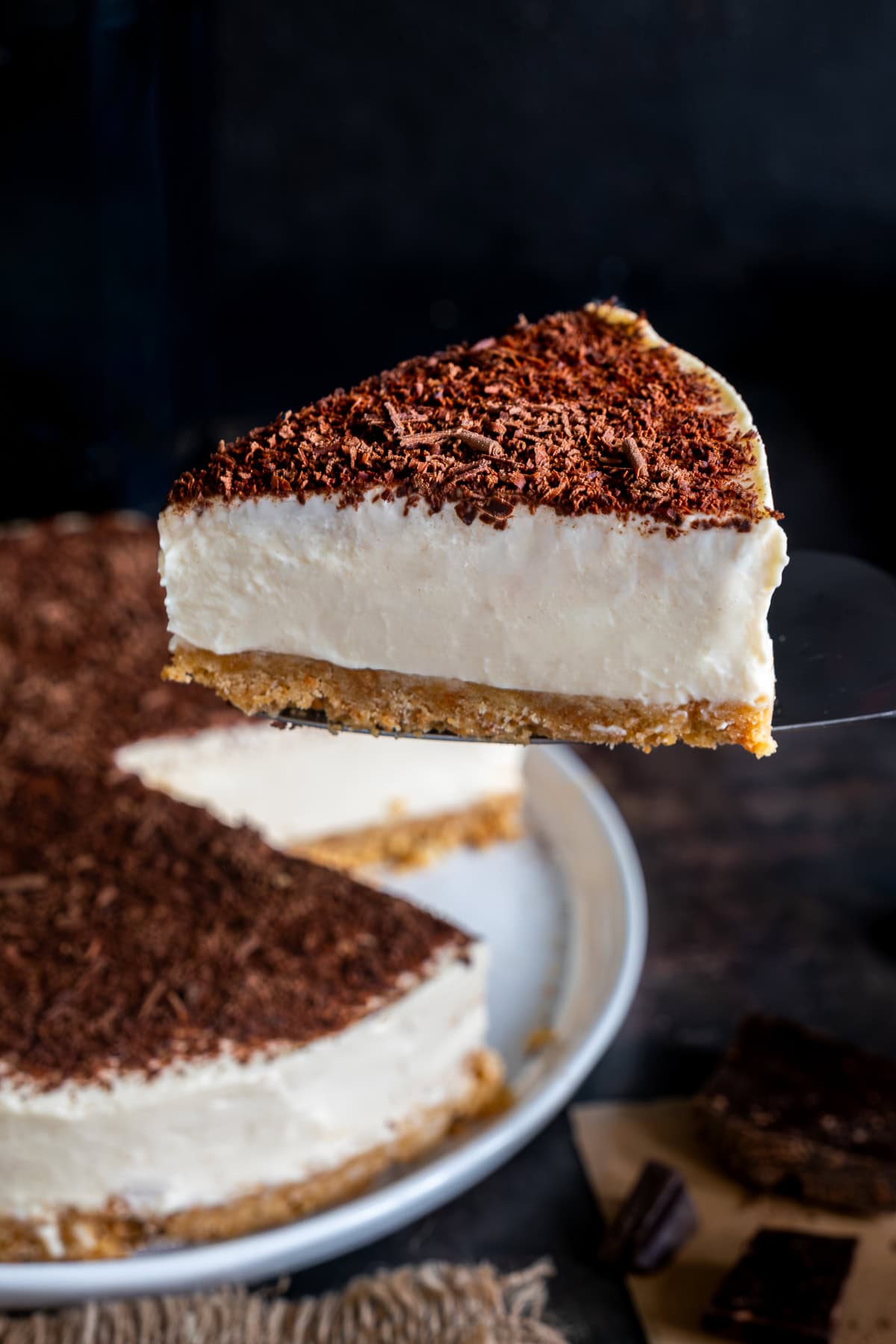 Easy Baileys Cheesecake on a serving plate. One slice has been cut and is being lifted out.