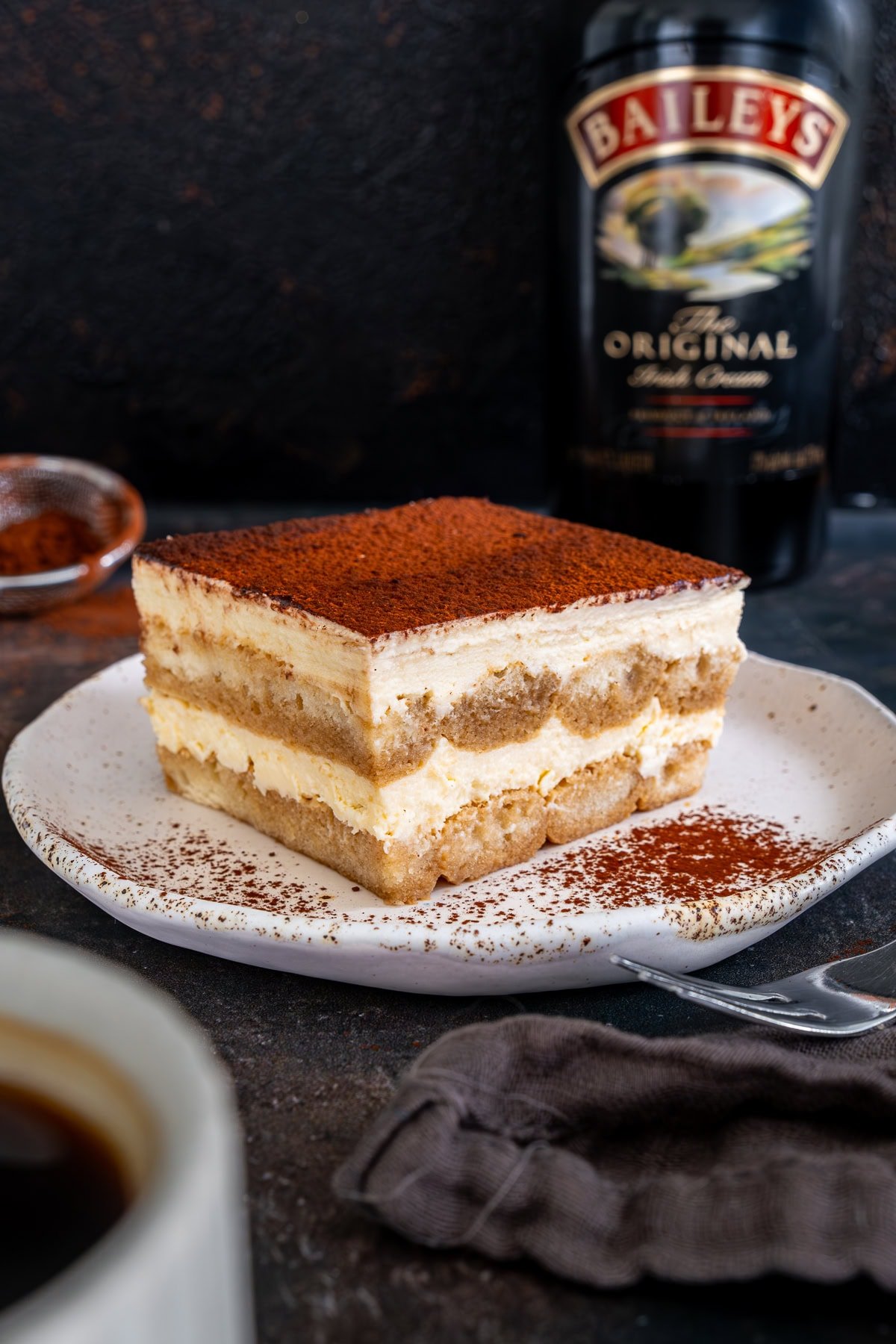 Once piece of Easy Baileys Tiramisù on a plate in front of a bottle of Baileys