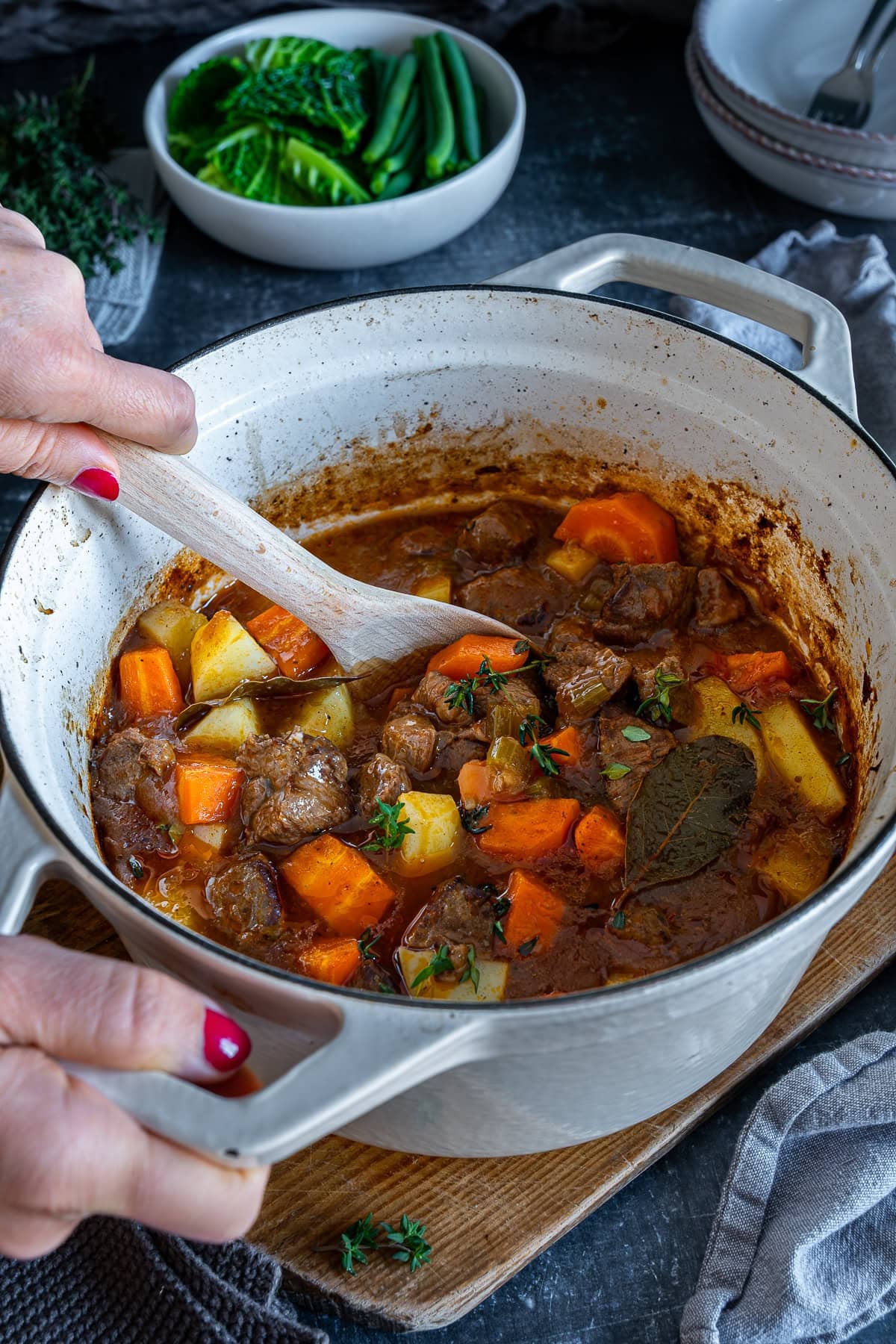 Woman's hands stirring Easy Beef Casserole with a wooden spoon.