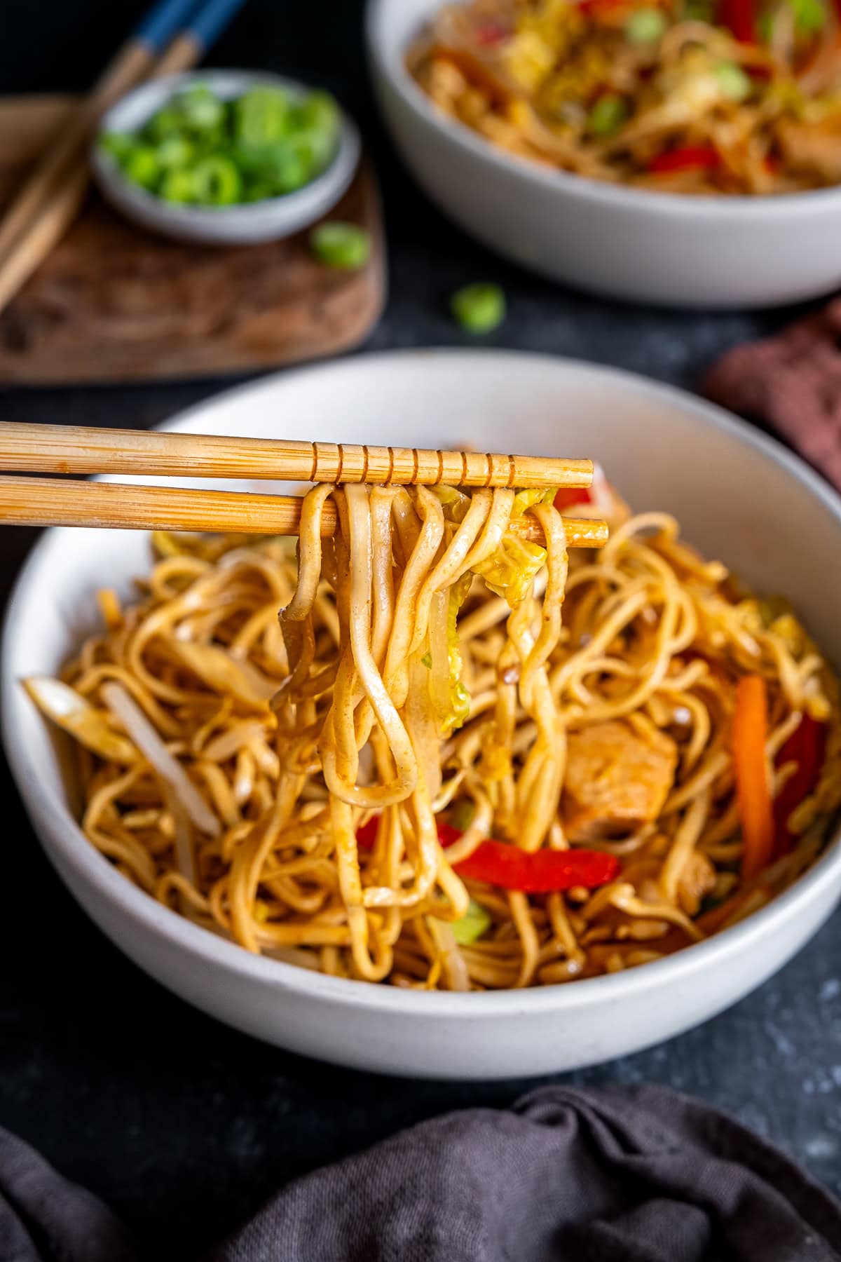 Noodles being lifted out of the bowl with chopsticks.