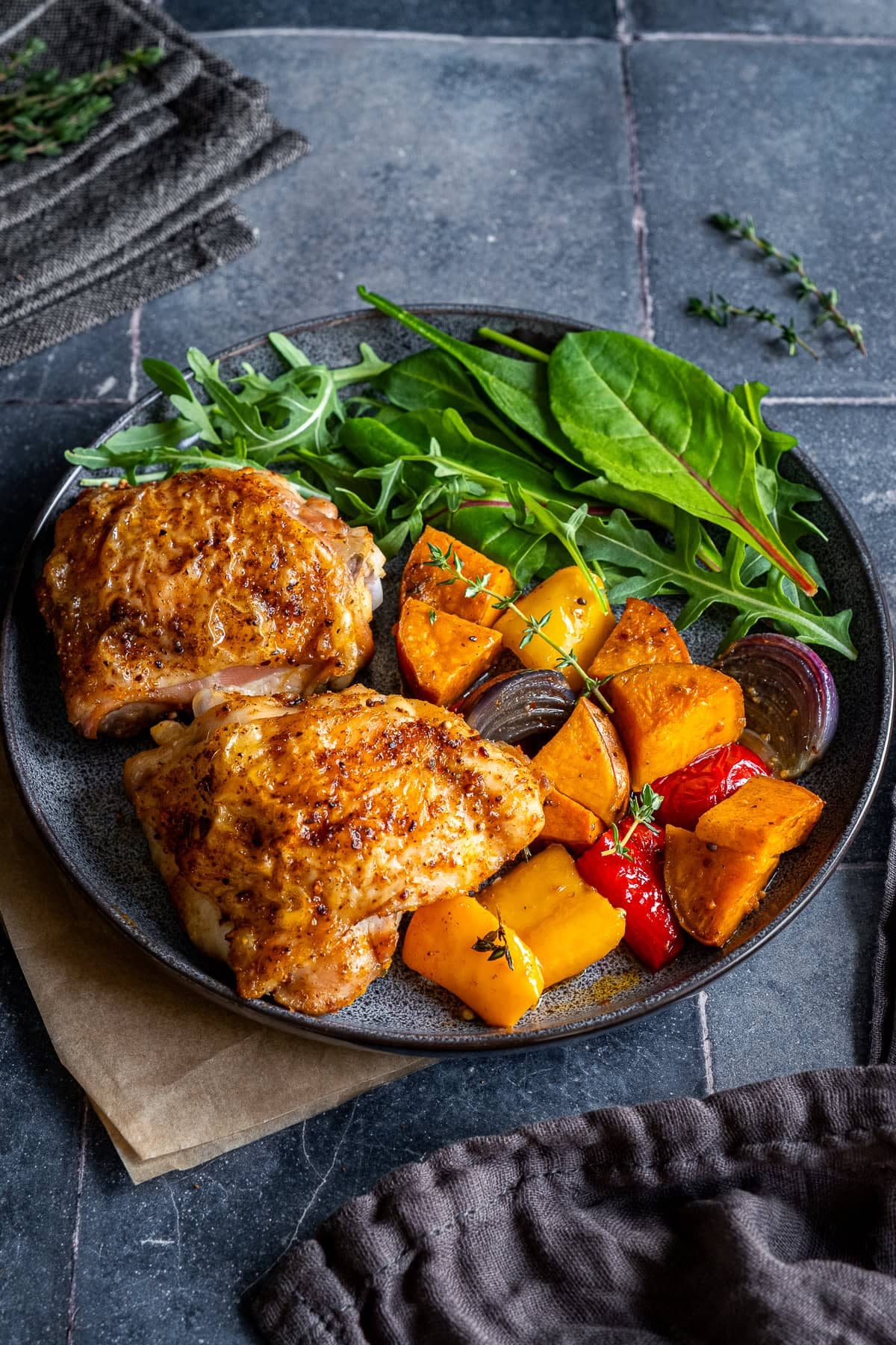 Closeup of Easy Chicken Thigh Traybake on a plate with salad.