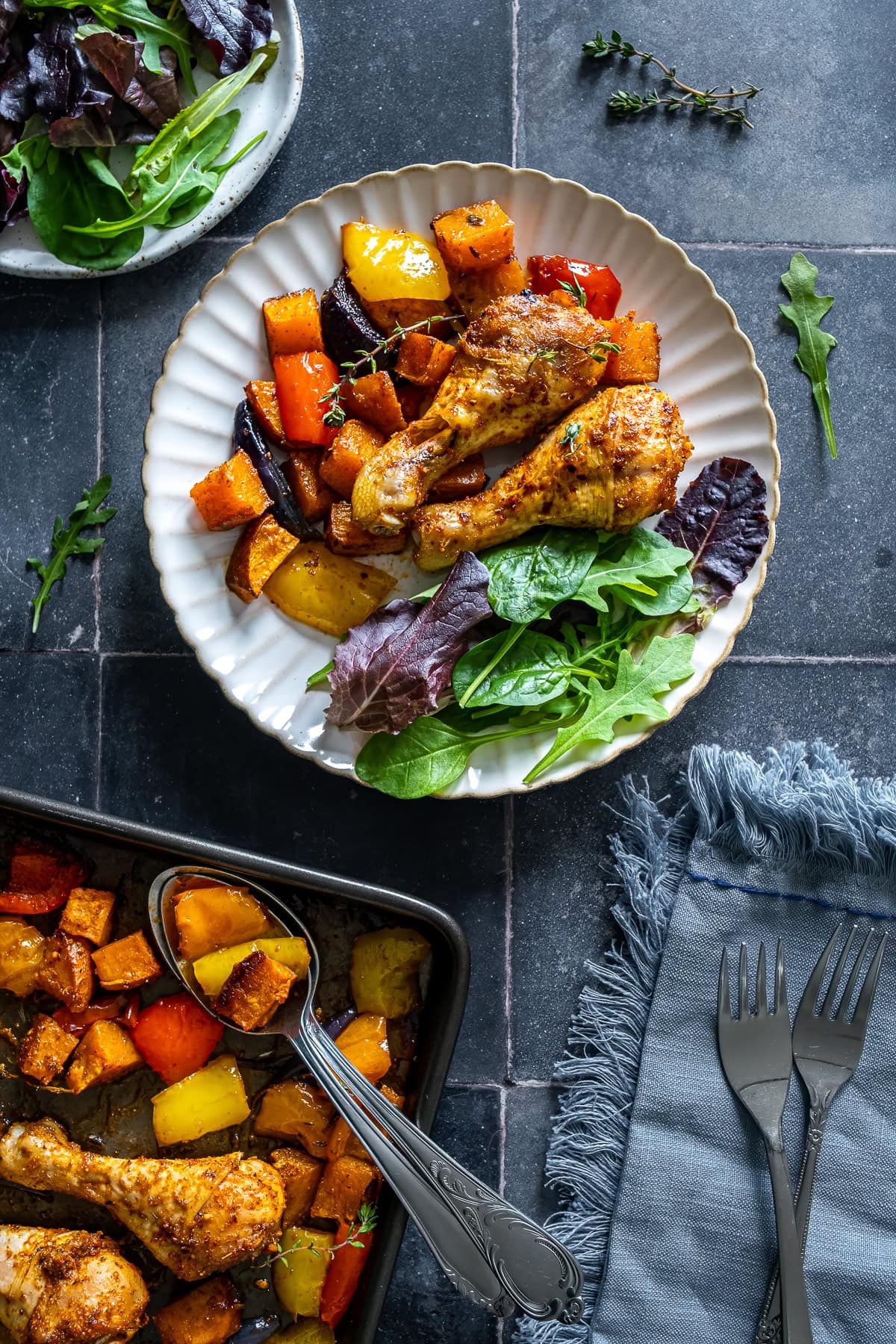 Overhead shot of Chicken Drumstick Traybake on a plate with salad leaves.