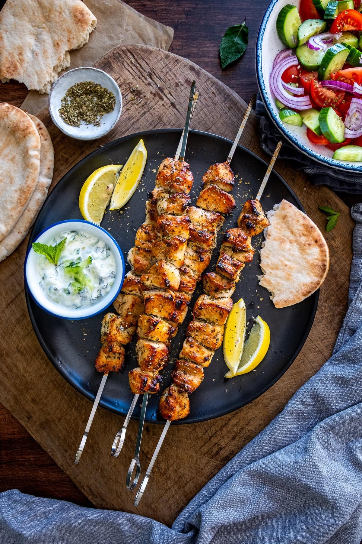 Overhead shot of 4 Greek Chicken Kebabs tzatziki, salad and pittas.