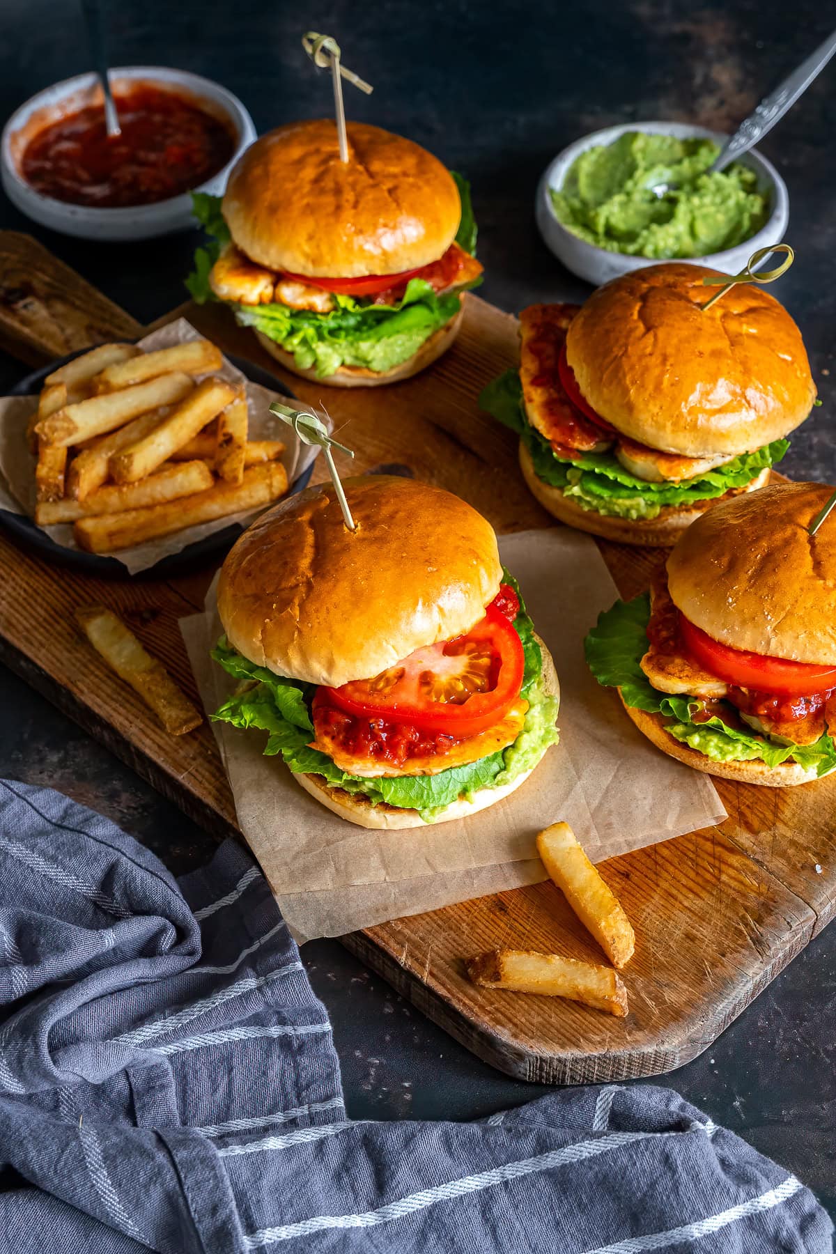 Four Halloumi Burgers on a board, with fries.