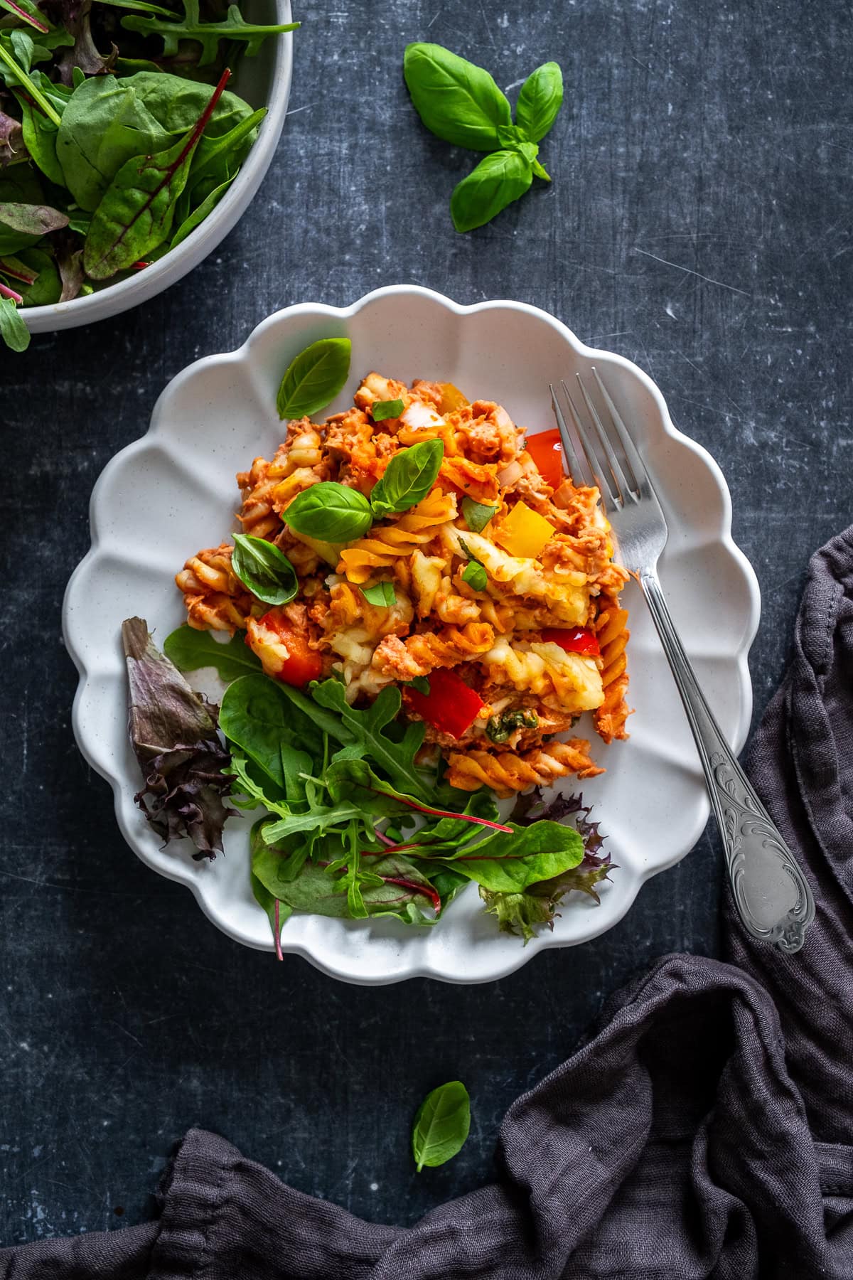 Creamy Tomato Tuna Pasta Bake on a plate, with a green salad.