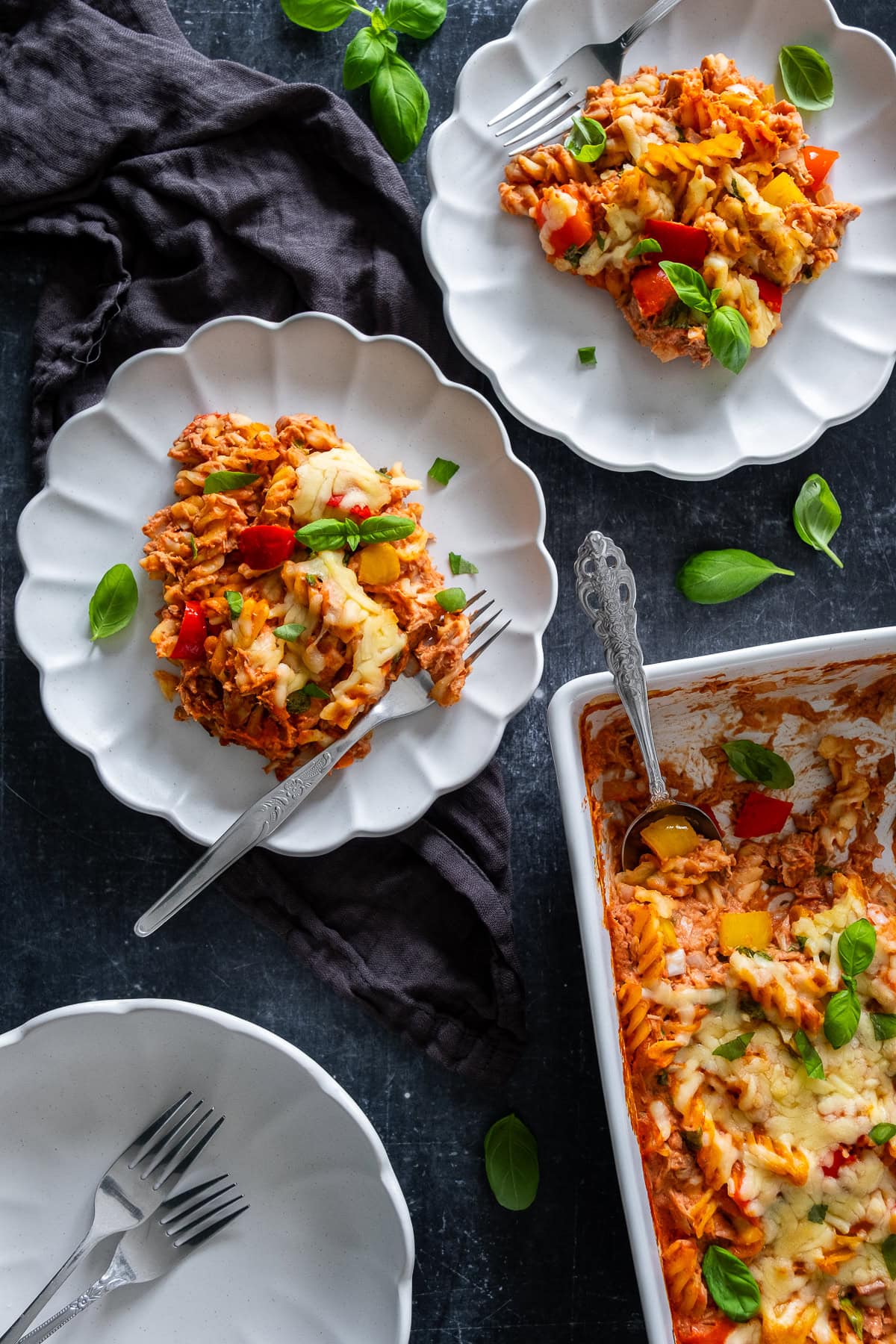 Overhead shot of Creamy Tomato Tuna Pasta Bake in the pan and on two plates.