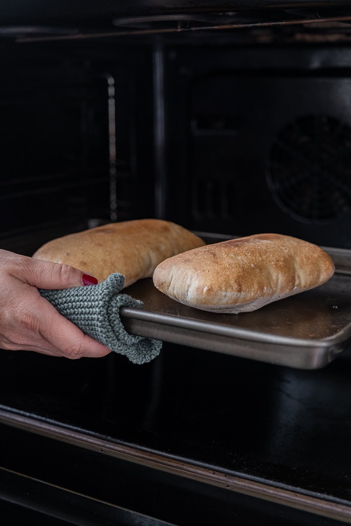 Image of perfectly puffed homemade Greek pitta breads coming out of the oven.