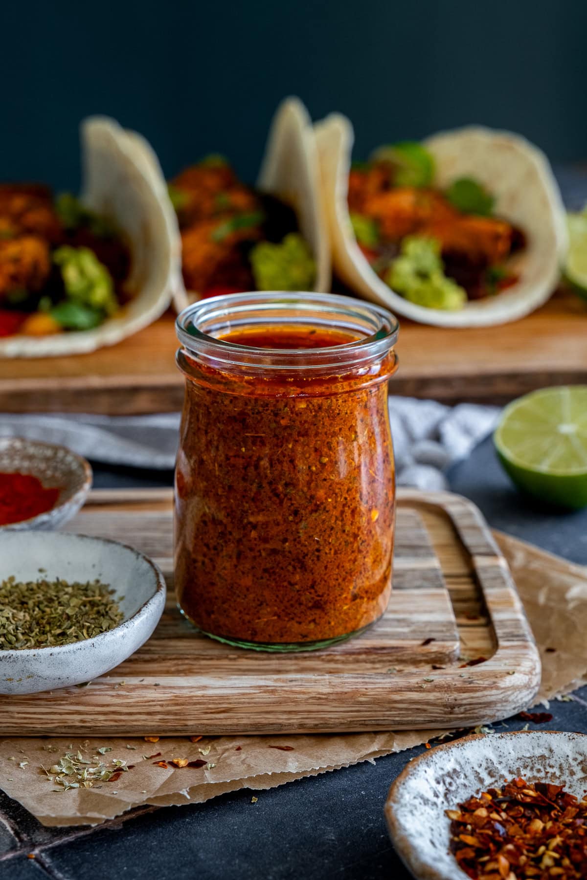 Closeup of Homemade Fajita Marinade in a small jam jar, with fajitas in the background.