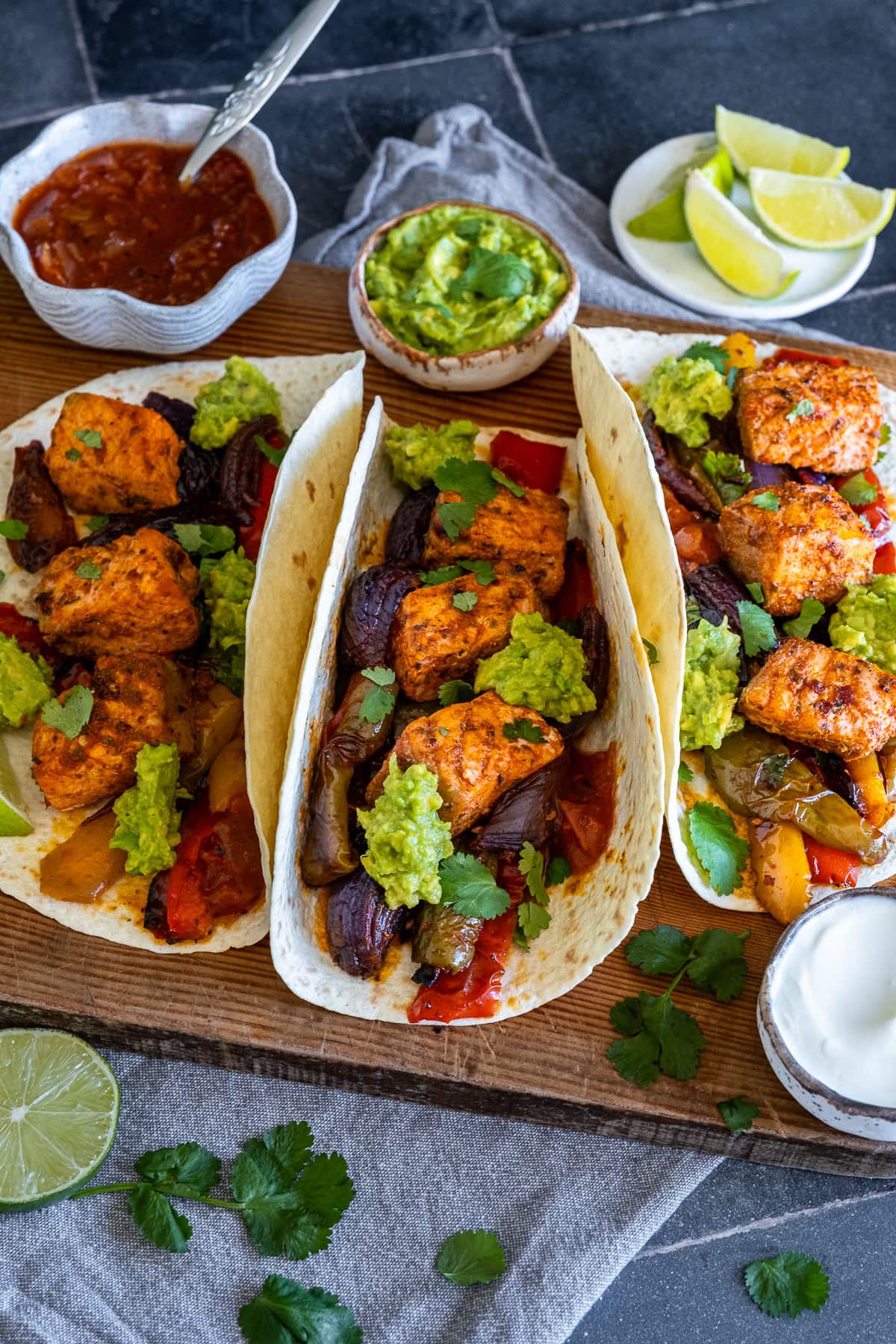 Closeup of 3 Salmon Fajitas on a board.