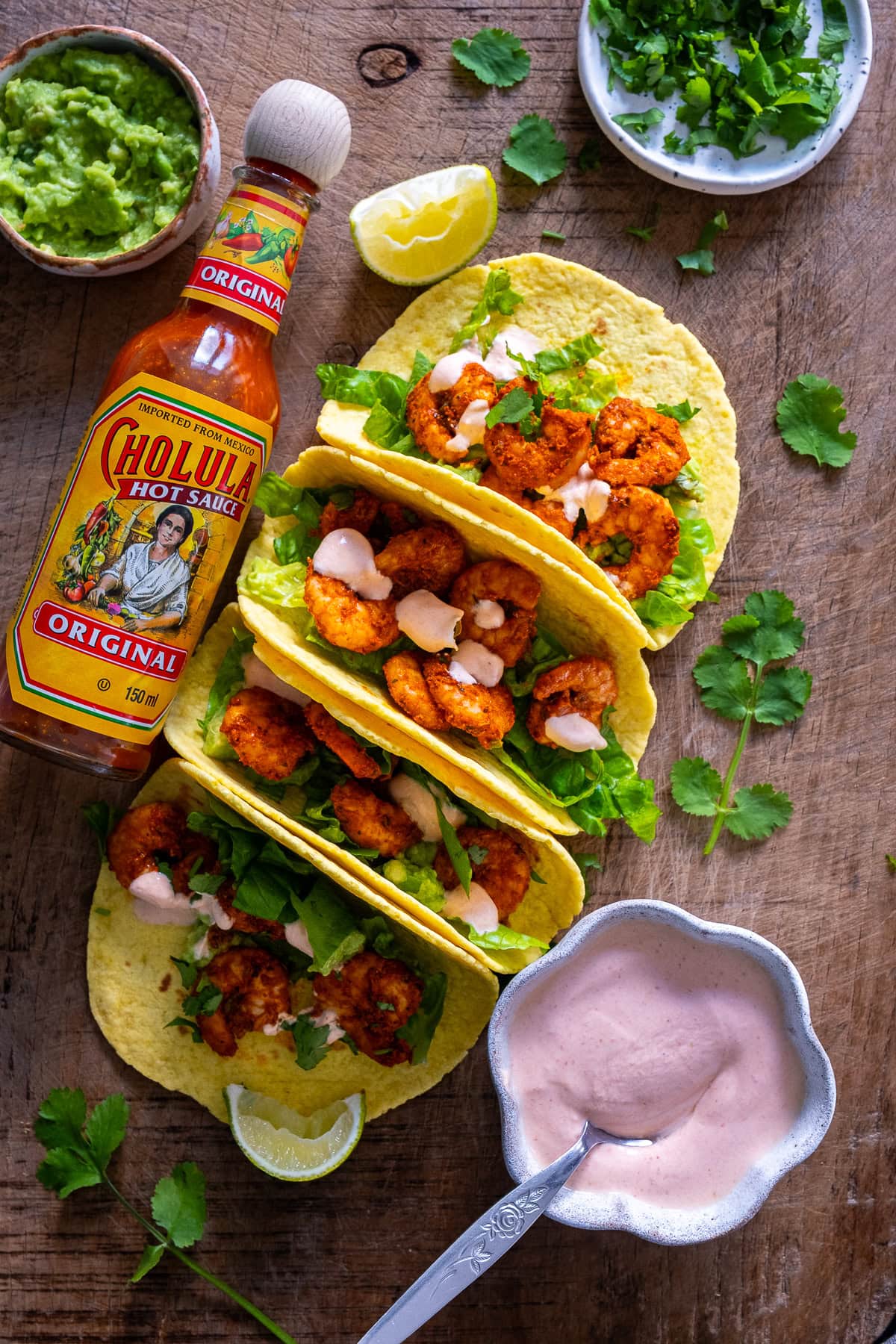 Overhead shot of 4 Easy Prawn Tacos with Pink Taco Sauce and Choula Hot Sauce.