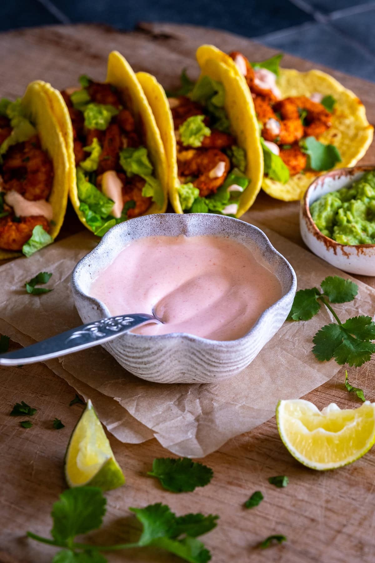 Pink Taco Sauce in a bowl in front of 4 prawn tacos.