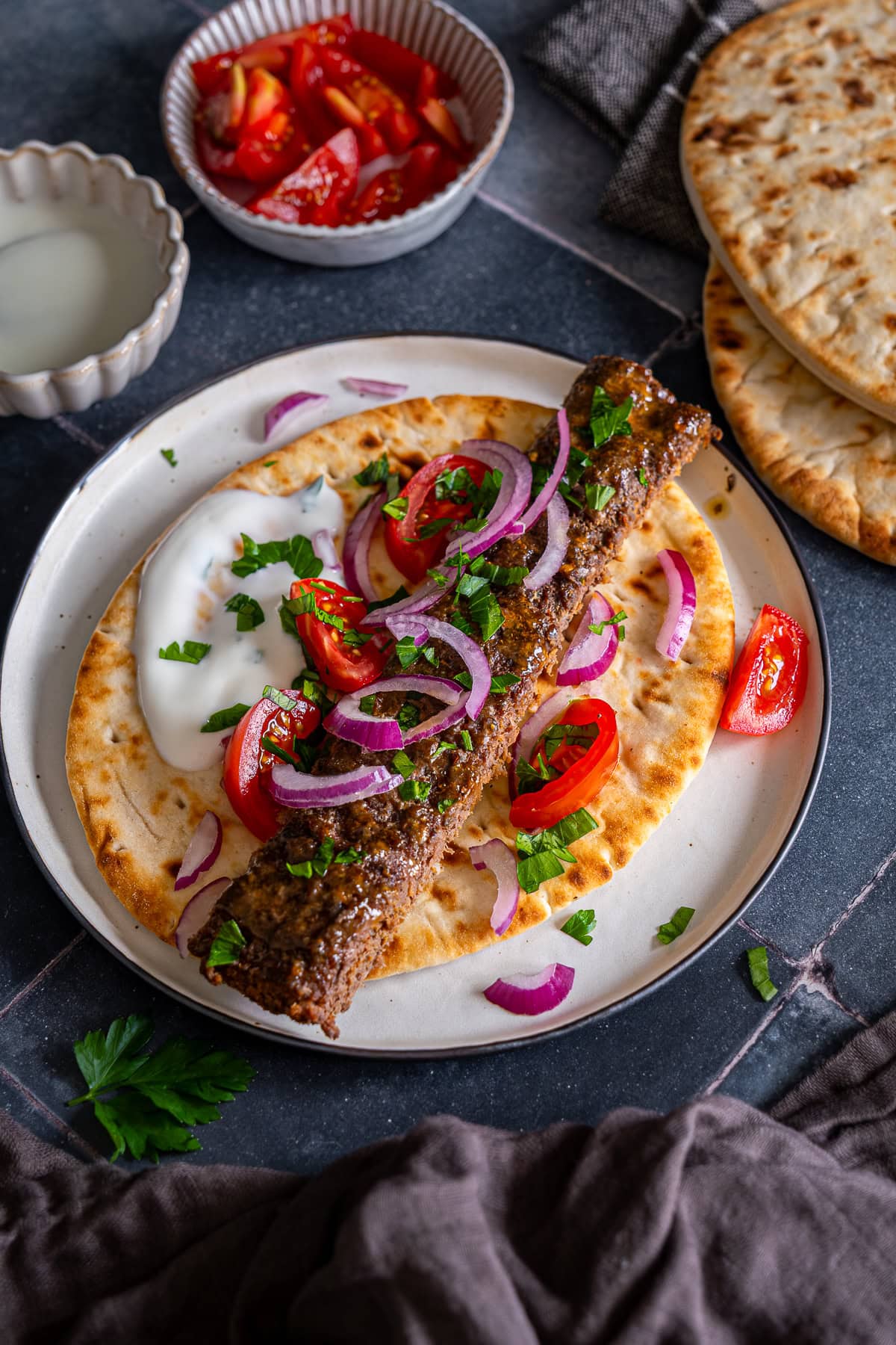 One Sheet Pan Beef Kebab on a flatbread with yogurt, red onions and tomatoes.